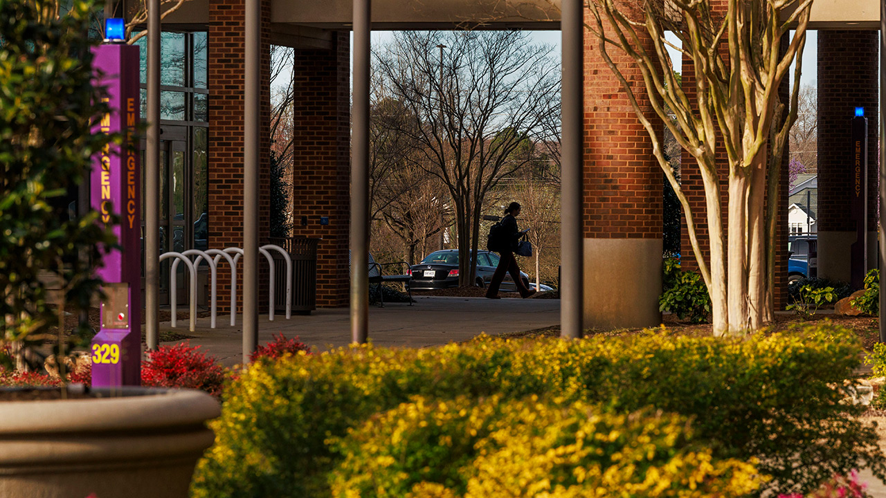 A student walks through columns of a building on East Carolina University?s campus.